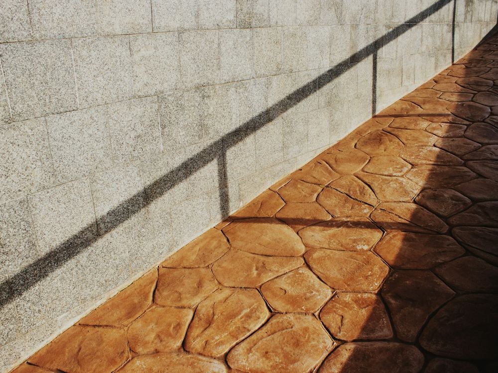 Stamped and colored concrete walk along a wall (illustrative photo)