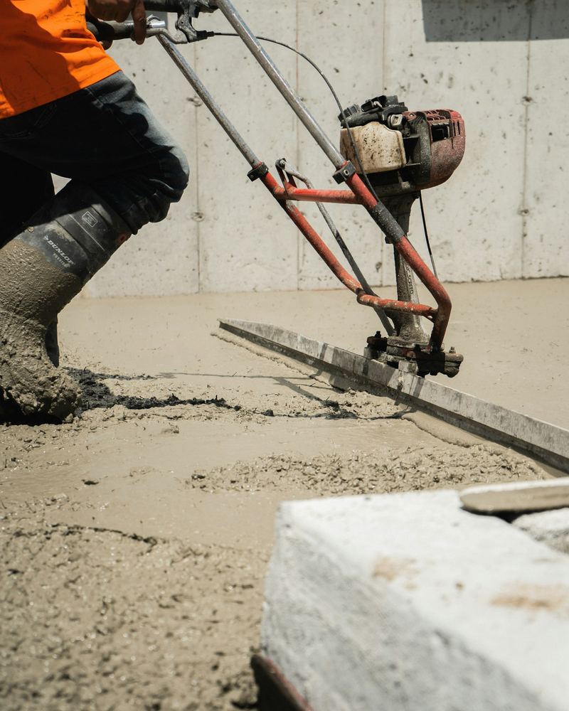 Power screed leveling fresh concrete (illustrative photo)