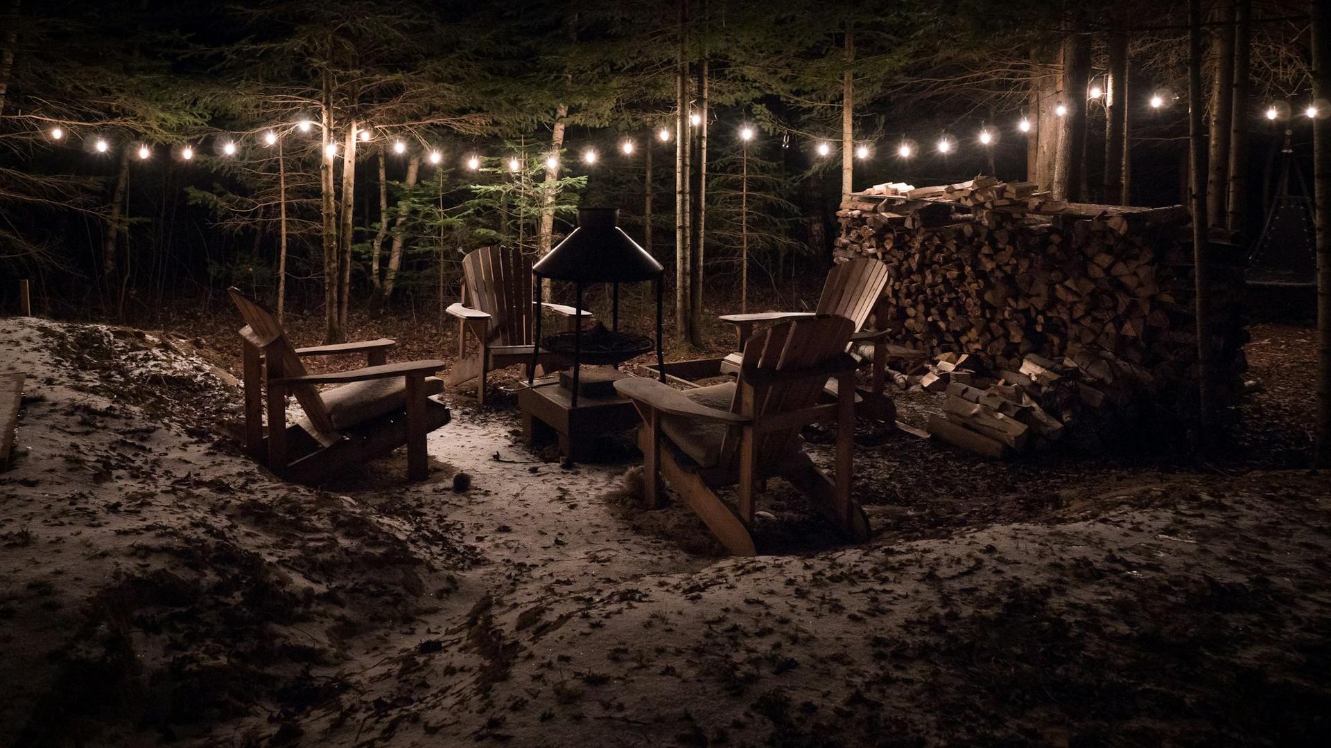 Fire pit and chairs under string lights at night