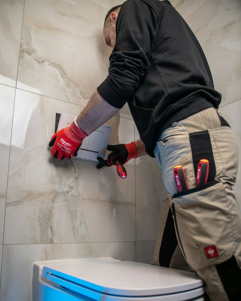 Plumber installing a wall-hung toilet (illustrative photo)