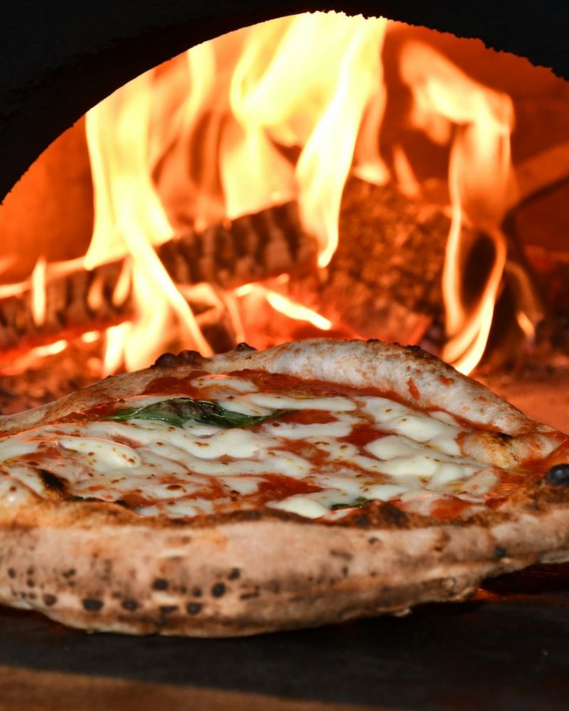 Pizza baking in front of open flames (illustrative photo)
