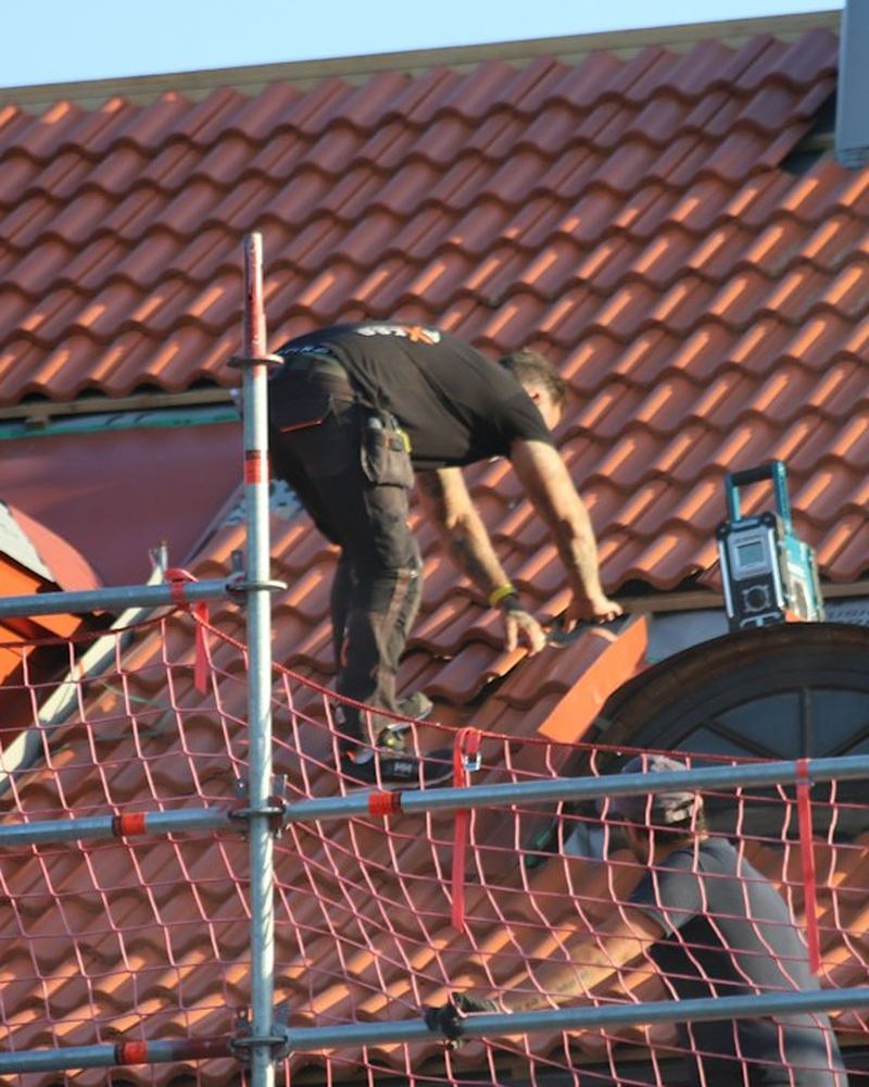 Roofer working on a roof from scaffolding (illustrative photo)