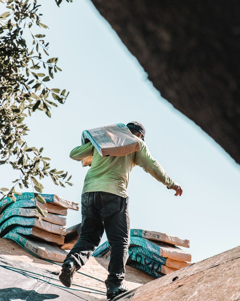 Roofer carrying bundles of shingles (illustrative photo)